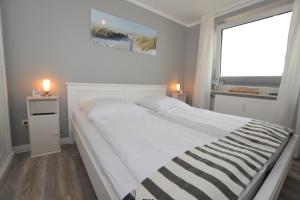een wit bed in een kamer met een raam bij MEERzeit - a64044 in Westerland