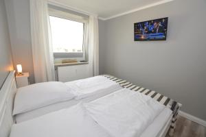een wit bed in een witte slaapkamer met een raam bij MEERzeit - a64044 in Westerland
