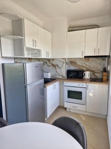 a kitchen with white cabinets and a stainless steel refrigerator at APART SUNNY BAY a SUNNY BEACH in Sunny Beach