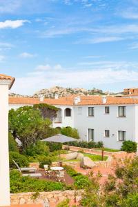 a large white building with a patio and an umbrella at Mangia's Santa Teresa Sardinia, Curio Collection by Hilton in Santa Teresa Gallura