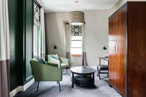 uma sala de estar com cadeiras verdes e uma mesa em The Inchcolm em Brisbane