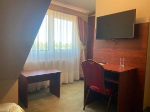 a room with a desk and a tv and a chair at Hotelik Zełwągi in Mikołajki