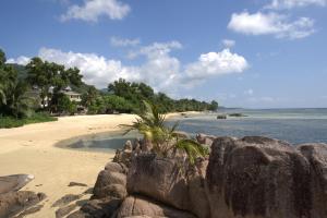 a beach with a rock wall and the ocean at Crown Beach Hotel Seychelles in Pointe Au Sel 