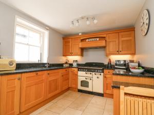 uma cozinha com armários de madeira e um fogão em Harbourside Cottage em Weymouth