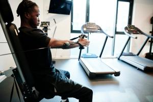 a man sitting on a treadmill in a gym at Private Bedrooms with Shared Kitchen, Studios and Apartments at Canvas Wembley in London in London