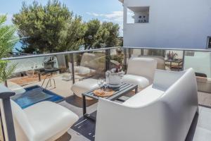 Un balcón con sillas blancas y una mesa. en Clauhomes Villa Al Mar Deluxe, en Tarragona