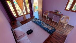 a bedroom with a bed and a desk and windows at Apna Ghar Hotel And Resort in Chaukori