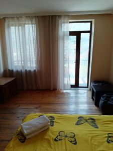 a bedroom with a yellow bed and a large window at Belas guesthouse in Stepantsminda