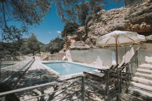 a swimming pool with an umbrella and a chair and an umbrella at Zos Suites in Kanakis