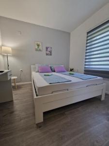 a bedroom with a large white bed with purple pillows at Visit Drežnica in Mostar