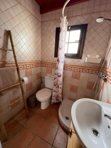 Un baño con inodoro, lavabo y ventana. en Casa Volcán, en La Costa