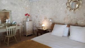1 dormitorio con cama, escritorio y espejo en Barn cottage en La Tour-Blanche