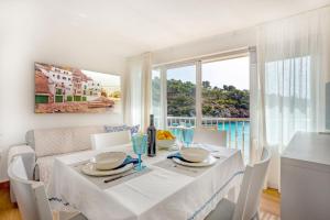 una sala da pranzo bianca con tavolo e finestra di Chalet Cal Tio Miquel direkt am Meer, mit Wifi a Cala Santanyi