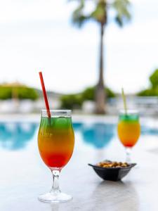 zwei Cocktails und eine Schüssel Essen auf einem Tisch in der Nähe eines Pools in der Unterkunft Manos Pension in Faliraki