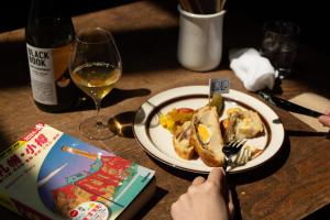 a table with a plate of food and a glass of wine at Untapped Hostel in Sapporo