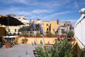 eine Terrasse mit Topfpflanzen, Tischen und Gebäuden in der Unterkunft HOPESTEL Secret Garden Napoli in Neapel