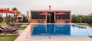 una piscina con sillas y sombrillas junto a un edificio en Igrane House en Marrakech