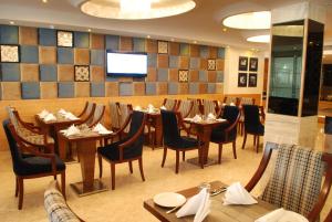 a restaurant with tables and chairs and a television at Glades Hotel in Chandīgarh