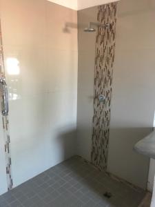 a shower in a bathroom with a tile floor at Big Cats Namibia Self Catering Farm Guesthouse in Outjo