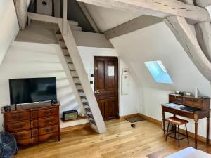 a room with a tv and a piano in a attic at Le Relais des Ducs : centre historique Dijon in Dijon