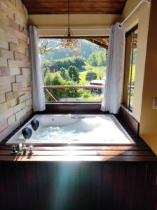 a jacuzzi tub in a room with a window at Estação 160 chalé Pico Agudo in Santo Antônio do Pinhal +61 photos
