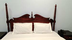 uma cama com cabeceira de madeira com lençóis e travesseiros brancos em Dev Sneh Residency em Jaipur mais 1 fotografia