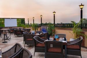 ein Restaurant mit Tischen und Stühlen auf einer Terrasse in der Unterkunft Glades Hotel in Chandīgarh