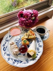 a plate of food on a table next to a window at ゲストハウスあさひのお宿 in Kurodahara