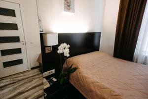 - une chambre avec un lit et un vase avec des fleurs blanches dans l'établissement Summit Villa, à Chişinău