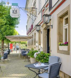 a patio with tables and chairs and an umbrella at Hotel Württemberger Hof in Öhringen