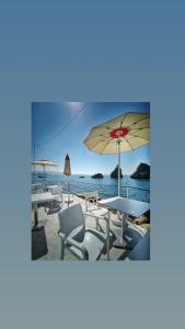 - une plage avec des tables, des chaises et un parasol dans l'établissement Casa Anselmo Guest House, à Pagani