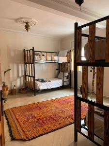 a room with two bunk beds and a rug at CHILL SURFER HOSTEL in Tamraght Ouzdar