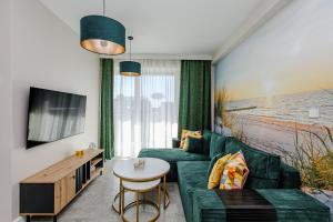 a living room with a green couch and a tv at Szum Fal Rewal in Rewal