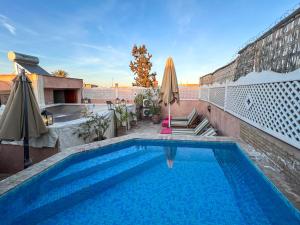 una gran piscina con sombrilla y sombrilla en Riad Matins De Marrakech, en Marrakech