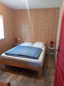 ein Schlafzimmer mit einem Bett in einem Zimmer mit Holzwänden in der Unterkunft Le chalet des Patures in Rochefort-Montagne