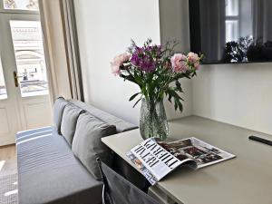 un jarrón de flores y una revista sobre una mesa en Anny 5 Apartamenty, en Cracovia