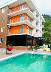 un hotel con piscina frente a un edificio en Orange Villa Kvariati en Kvariati