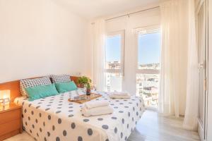 a white bedroom with a large bed with blue pillows at Apt Parque Fuengirola 800mt From Sea - Happy rentals in Fuengirola