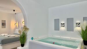 a white room with a bath tub with plants at Santorini Miracles Suites in Perissa