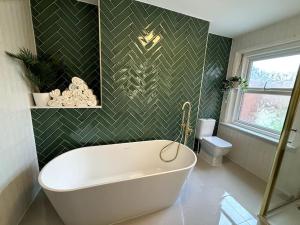 a bathroom with a white tub and a toilet at Casa 135, Sauna, Firepit, BBQ in Ringwood