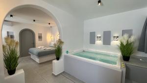 佩里薩的住宿－Santorini Miracles Suites，一间带植物浴缸和床的浴室
