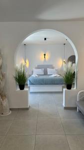 佩里薩的住宿－Santorini Miracles Suites，一间卧室配有一张床和两盆植物