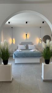 a bed in a room with two potted plants at Santorini Miracles Suites in Perissa