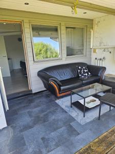 a black leather couch sitting on a patio at Montana Guest House. in Lillestrøm