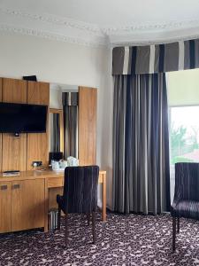 um quarto com 2 cadeiras, uma secretária e uma televisão em The Strathearn Hotel em Fife
