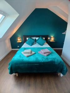 a bedroom with a large blue bed with two pillows at Gite avec Spa Le Rubis proche des plages du Débarquement Manche Normandie in Joganville