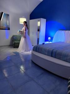 une femme en tenue de mariage debout à côté d'un lit dans l'établissement B&B SOGNANDO VIETRI, à Aversa