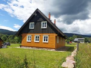 een houten huis met een zwart dak bij Chalupa Jadrná 2 in Orlické Záhoří 