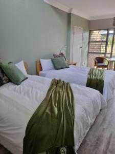 2 camas con sábanas blancas y almohadas verdes en Middelburg Country Club, en Middelburg 16 fotos más