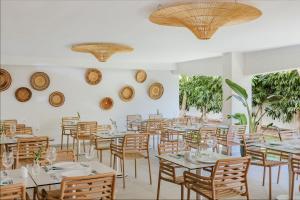 uma sala de jantar com mesas, cadeiras e janelas em Nissi Park Hotel em Agia Napa